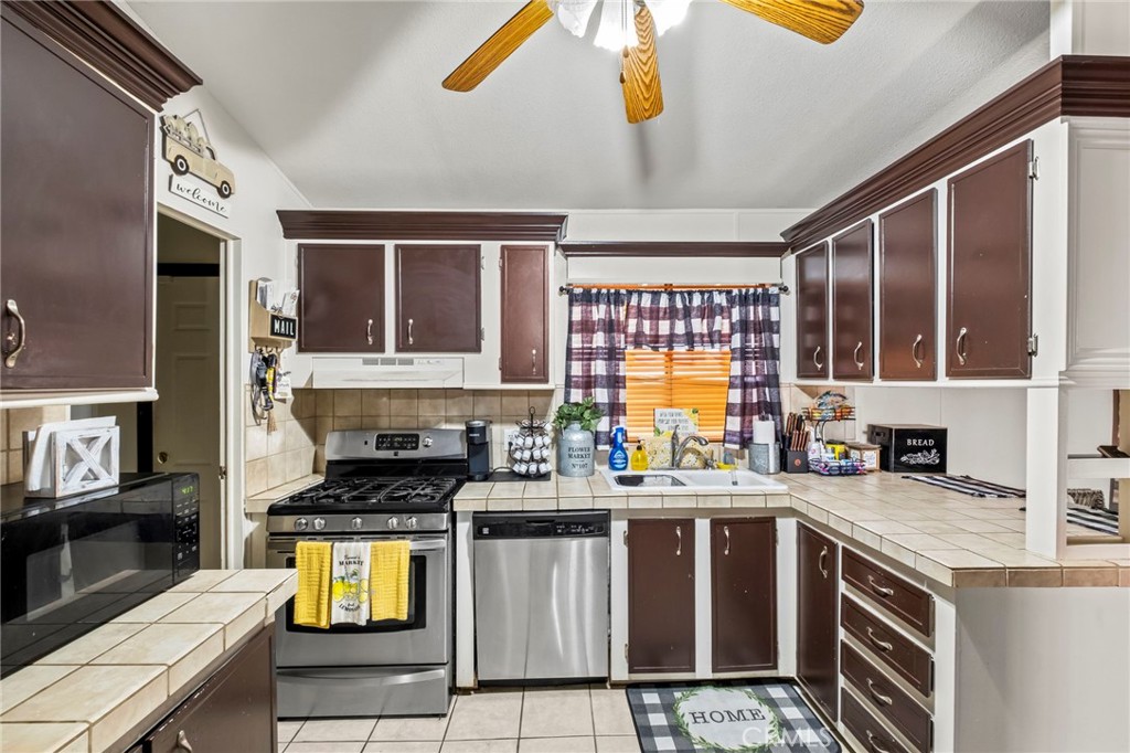 24847 Split Rail Road Wildomar, CA 92595 - Photo 4 of 45 a kitchen with stainless steel appliances a stove a sink cabinets and a window