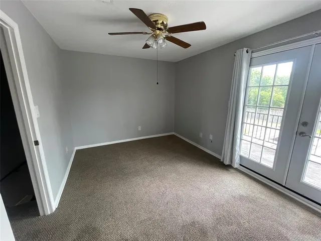 an empty room with a window and a ceiling fan