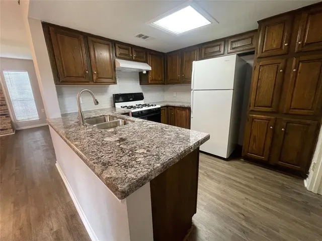 a kitchen with granite countertop stainless steel appliances a refrigerator and wooden cabinets
