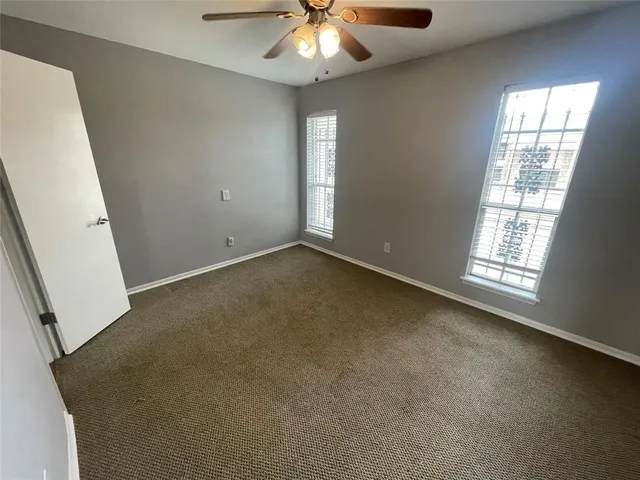 an empty room with chandelier fan and windows