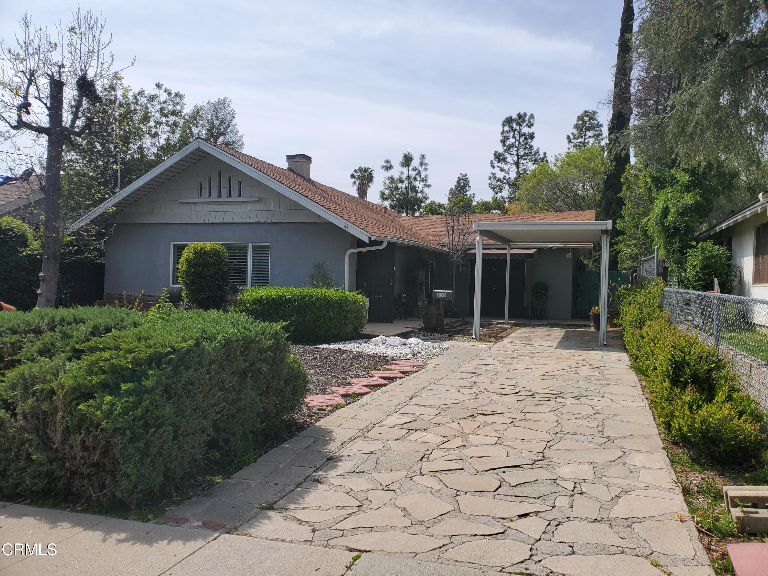 a front view of a house with a yard and potted plants