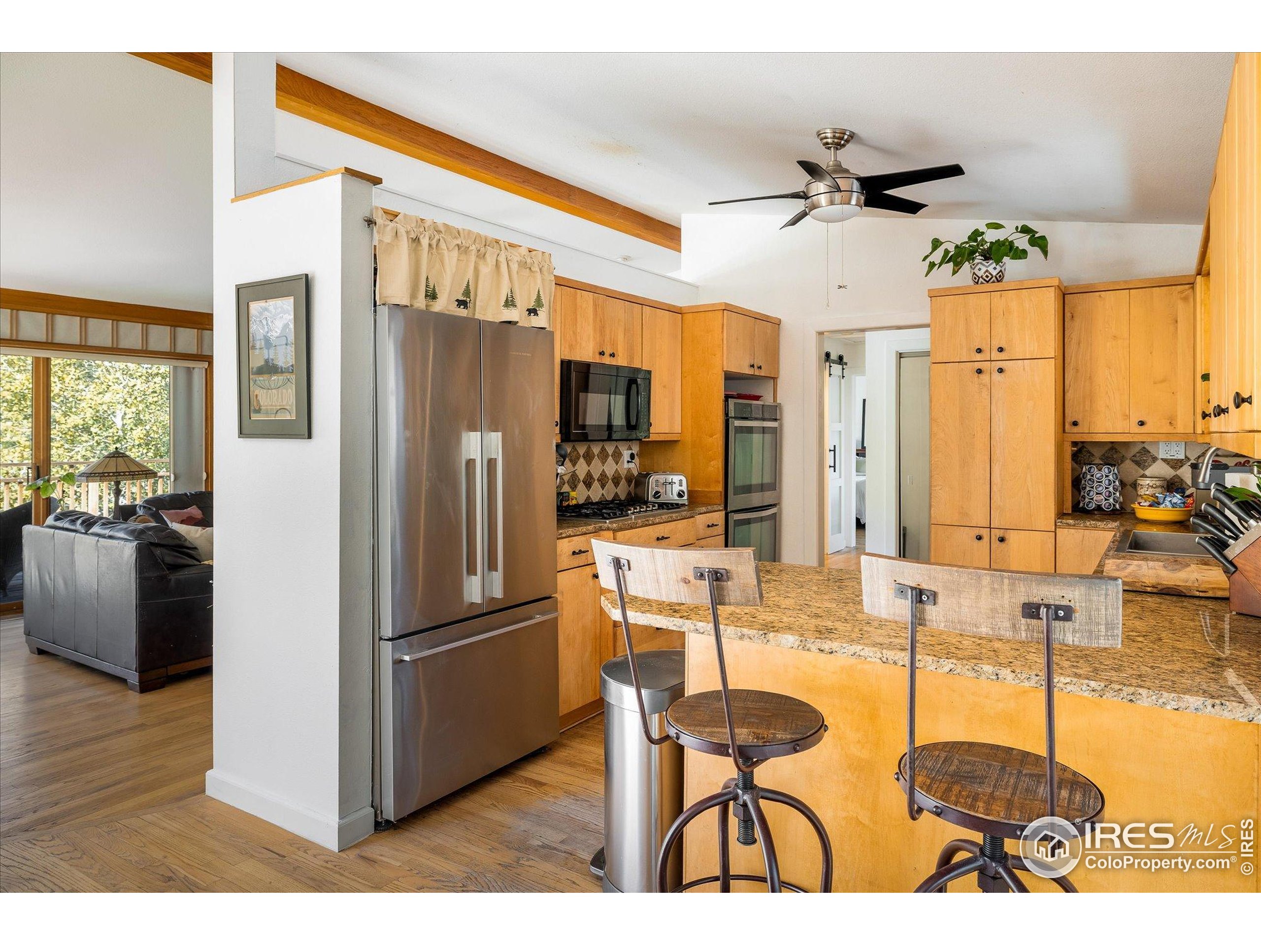 11935 Vonnie Claire Road Golden, CO 80403 - Photo 21 of 42 a kitchen with stainless steel appliances kitchen island granite countertop a refrigerator a stove and a dining table with wooden floor