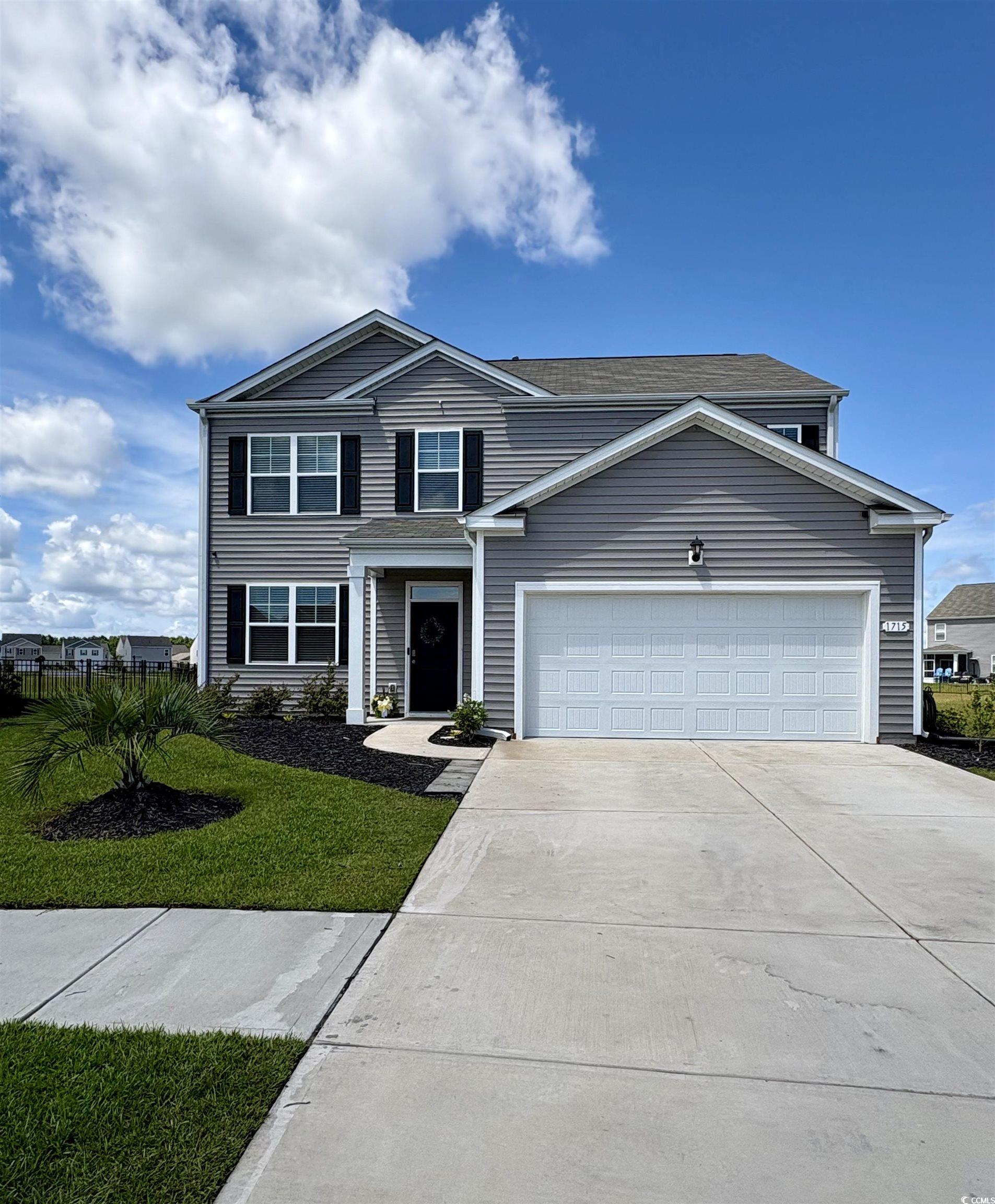 Traditional-style home with driveway, a garage, and a front yard