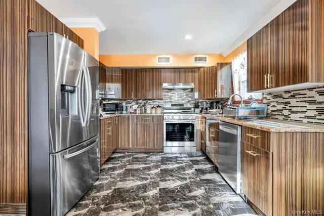 a kitchen with stainless steel appliances kitchen island granite countertop a sink refrigerator and cabinets
