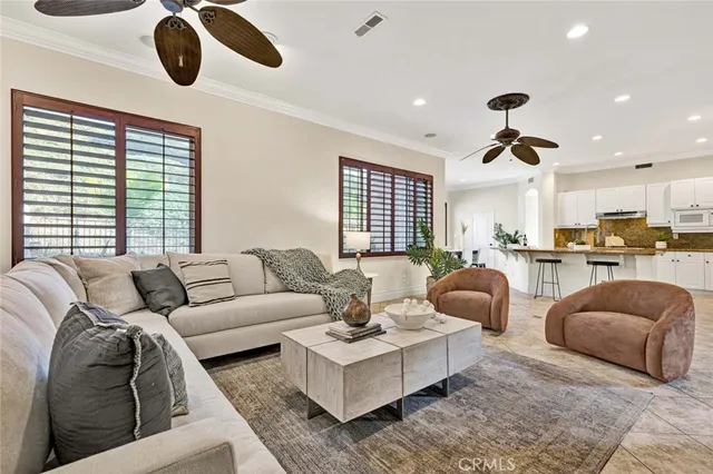 a living room with furniture ceiling fan and a large window