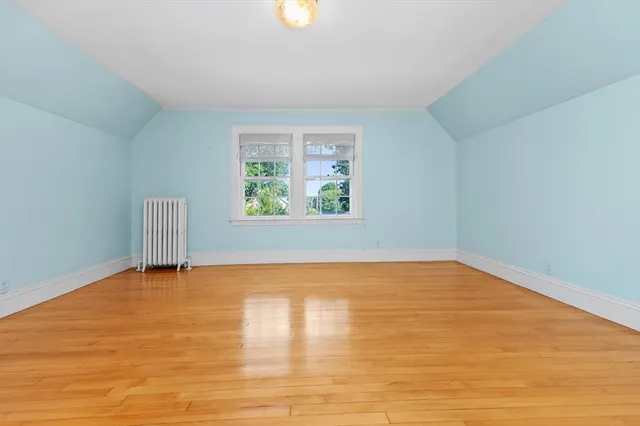 a view of an empty room with window and wooden floor