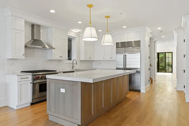 a large kitchen with stainless steel appliances granite countertop a stove a sink a refrigerator and a wooden floor