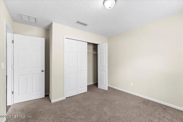 a view of an empty room with closet and a window