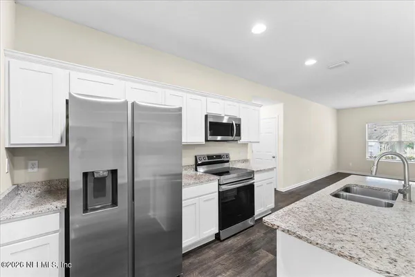 a large kitchen with stainless steel appliances granite countertop a granite counter tops and white cabinets