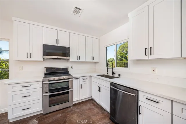 a kitchen with a sink cabinets appliances and a window