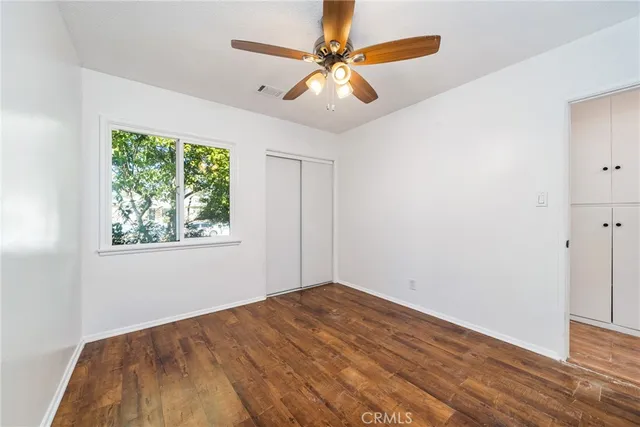a view of empty room with wooden floor and fan