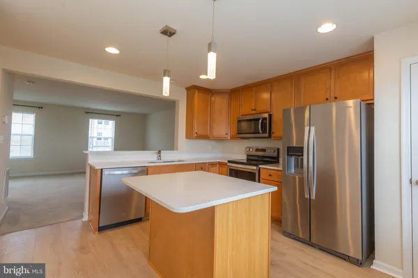 a kitchen with stainless steel appliances granite countertop a stove a sink a refrigerator white cabinets and wooden floor
