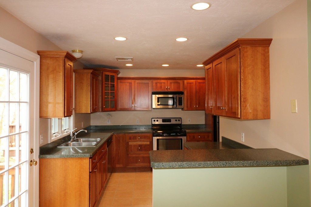 68 Brookfield Road, Unit 202 Charlton, MA 01507 - Photo 3 of 13 a kitchen with stainless steel appliances granite countertop a stove a sink a microwave a refrigerator and cabinets with wooden floor