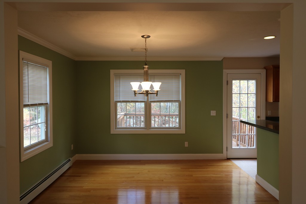 68 Brookfield Road, Unit 202 Charlton, MA 01507 - Photo 4 of 13 an empty room with wooden floor chandelier and windows