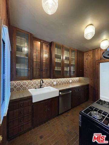 a kitchen with a sink and a stove with wooden floor