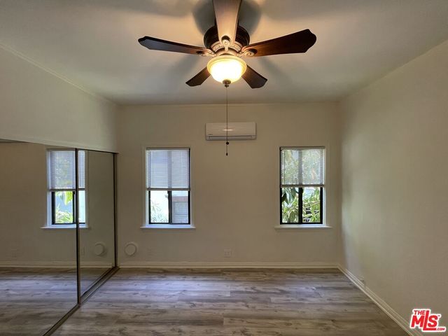 a view of an empty room with window and chandelier fan