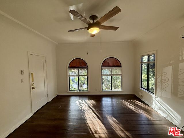 a view of empty room with wooden floor and fan
