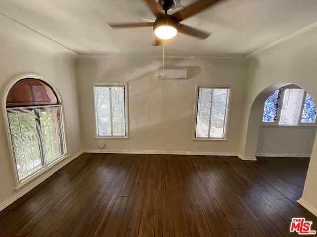 a view of an empty room with wooden floor ceiling fan and a window