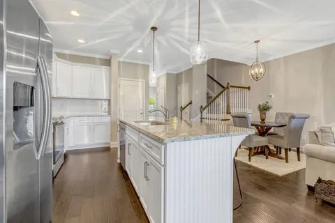 a kitchen with stainless steel appliances granite countertop a kitchen island hardwood floor and a sink