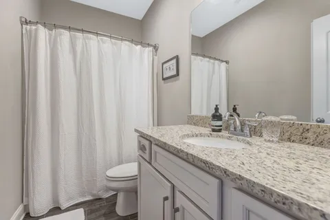 a bathroom with a granite countertop sink toilet and a mirror
