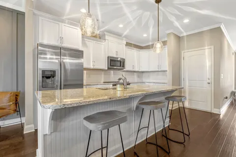 a kitchen with stainless steel appliances granite countertop a sink refrigerator and cabinets