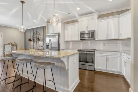 a kitchen with stainless steel appliances granite countertop a stove a sink a microwave a refrigerator and white cabinets