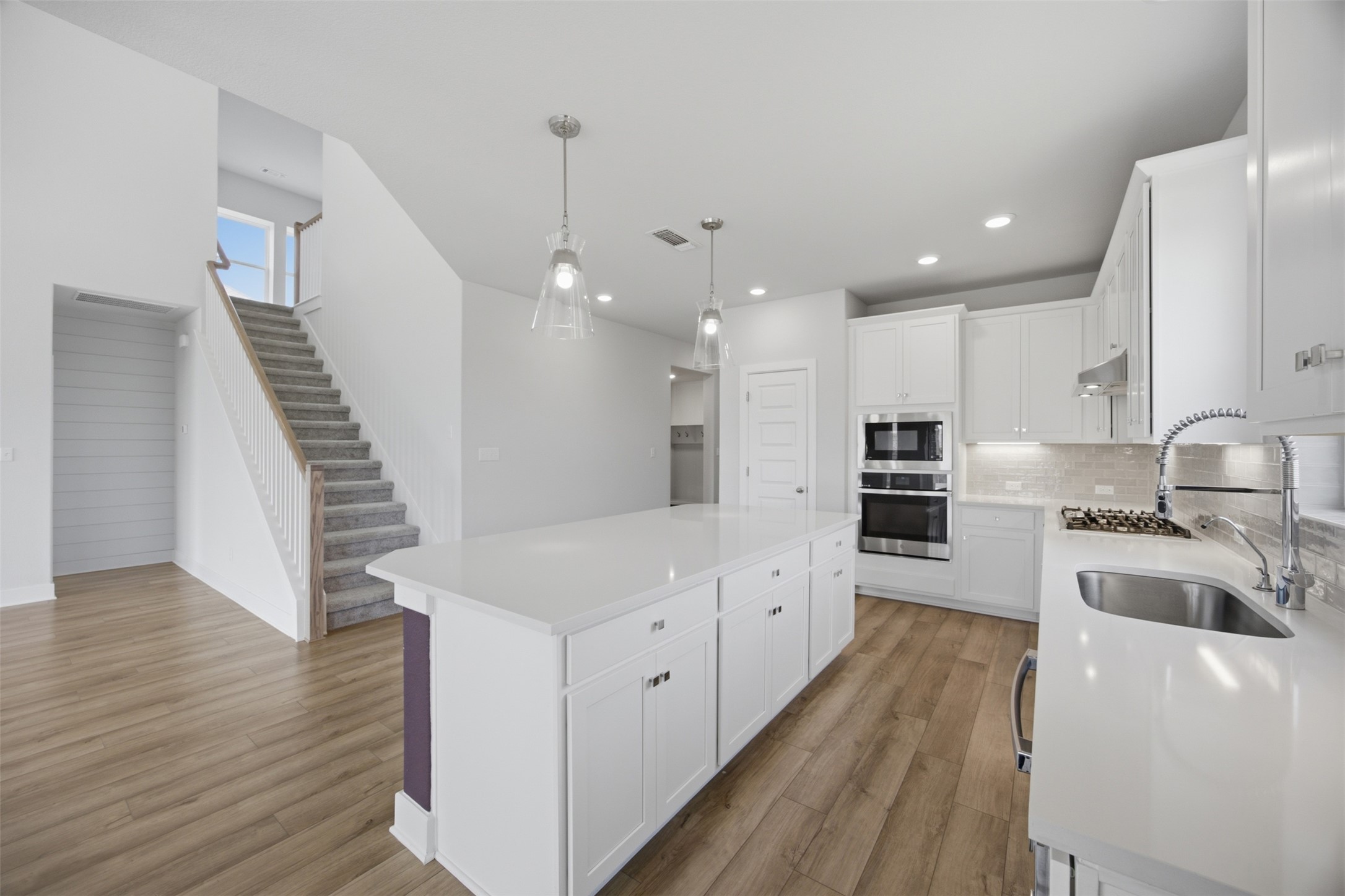 2101 Little Snake Way Georgetown, TX 78633 - Photo 16 of 37 White cabinetry, sleek appliances, and wood flooring create a crisp, modern kitchen perfect for entertaining.