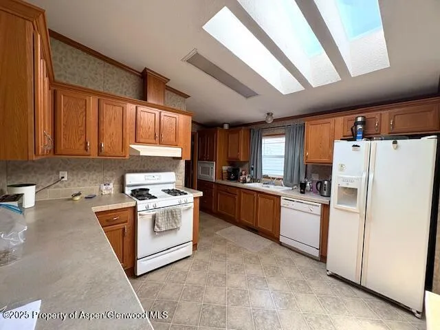 a kitchen with a refrigerator a stove a sink dishwasher and wooden cabinets with wooden floor