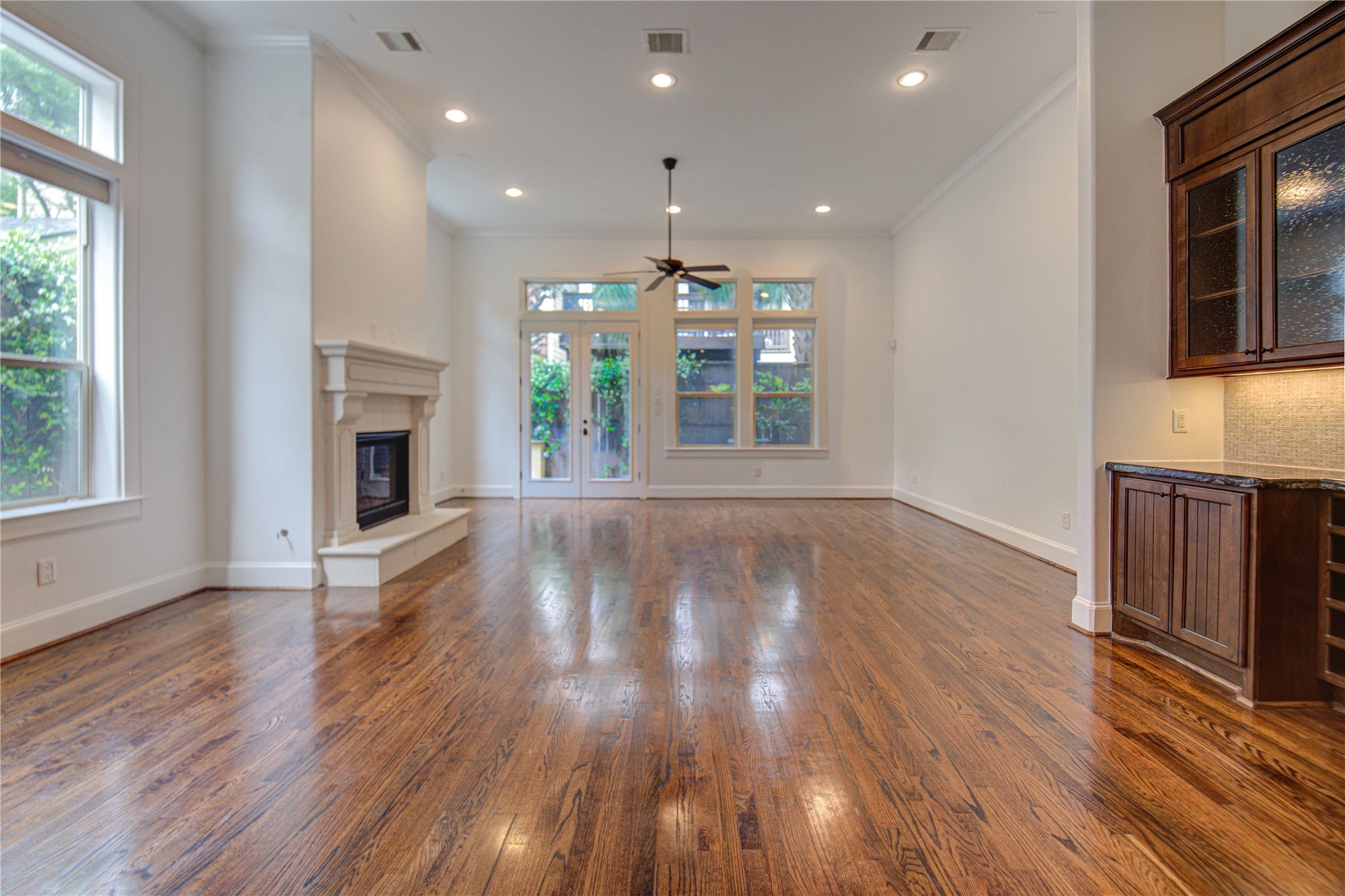 6520 Rodrigo Street Houston, TX 77007 - Photo 12 of 44 Light-filled living area with soaring ceilings, rich hardwood floors, expansive windows, and a statement fireplace creating an inviting atmosphere.