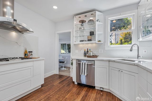 a kitchen with granite countertop white cabinets and wooden floor