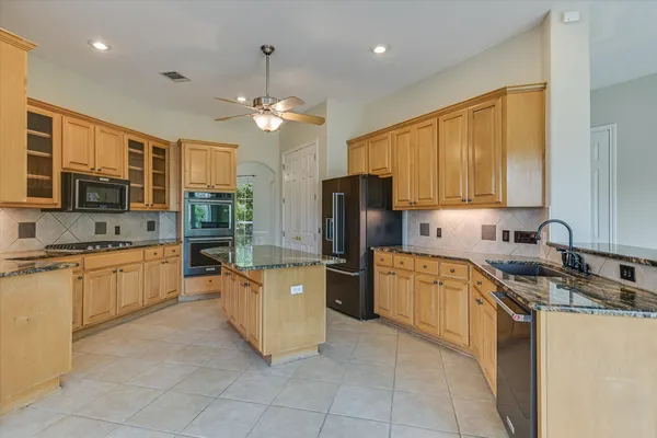 a kitchen with stainless steel appliances granite countertop a refrigerator a stove top oven a sink dishwasher and wooden cabinets