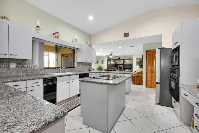 a kitchen with stainless steel appliances granite countertop a table chairs sink and cabinets
