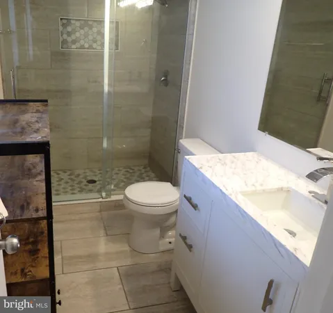 a bathroom with a granite countertop sink a toilet and shower