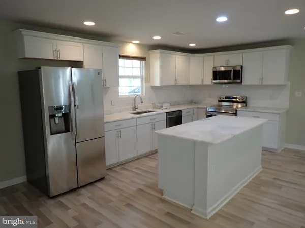 a kitchen with a sink a refrigerator a microwave and cabinets