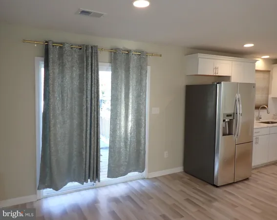 a view of a kitchen with wooden floor and refrigerator