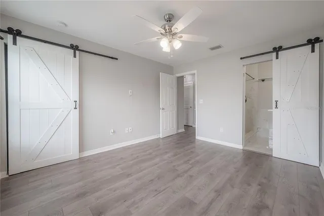 a view of an empty room with a ceiling fan and a hardwood floor