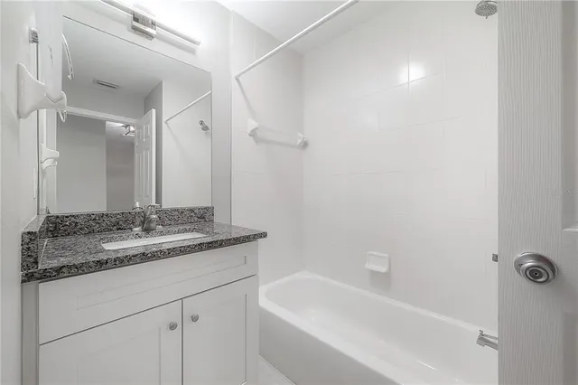 a bathroom with a granite countertop sink a mirror and a bathtub