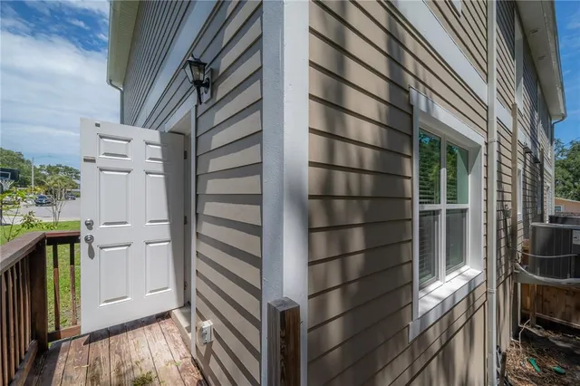 a backyard of a house with table and chairs potted plants and large tree