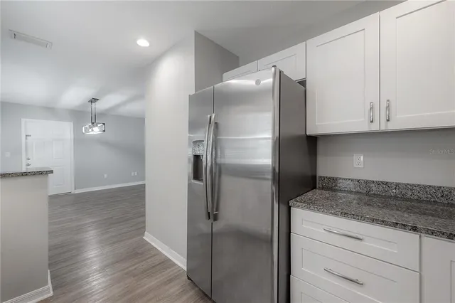 a kitchen with granite countertop a refrigerator and a stove top oven