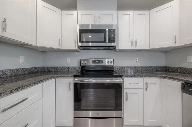 a kitchen with granite countertop white cabinets and stainless steel appliances