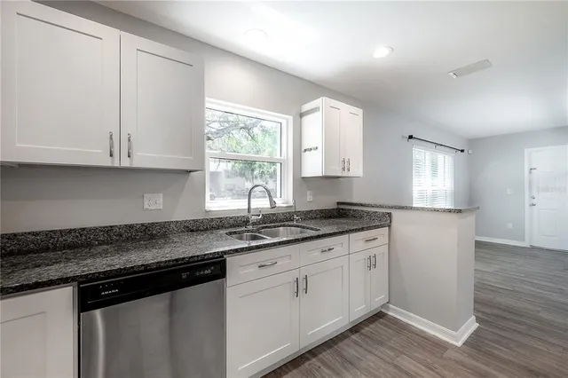 a kitchen with granite countertop white cabinets and a sink