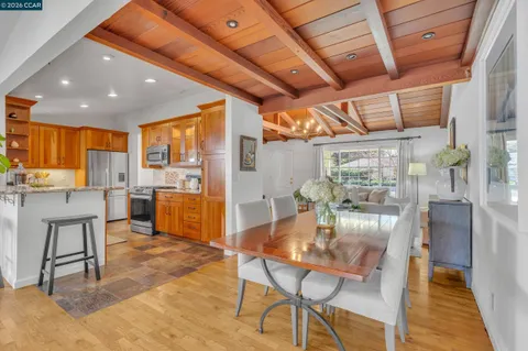 a dining room with stainless steel appliances kitchen island granite countertop a table chairs and a chandelier
