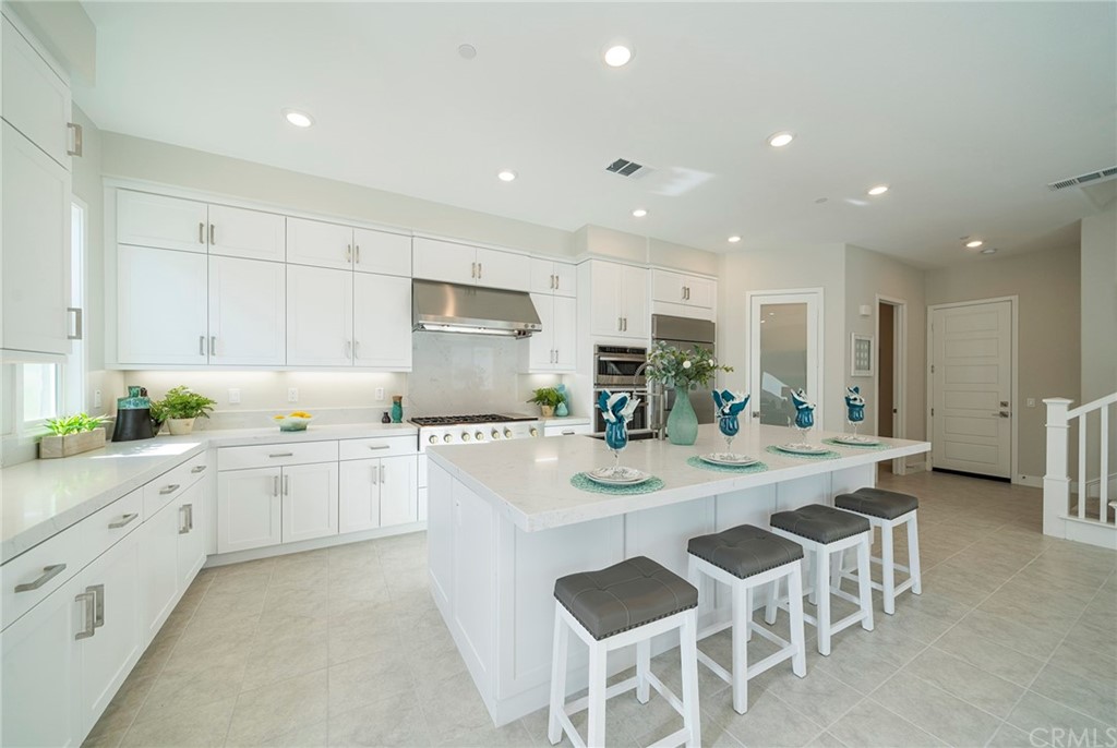 219 Chorus Irvine, CA 92618 - Photo 4 of 24 a kitchen with stainless steel appliances granite countertop a table chairs sink refrigerator and cabinets