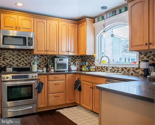 a kitchen with stainless steel appliances granite countertop a stove a sink and a microwave
