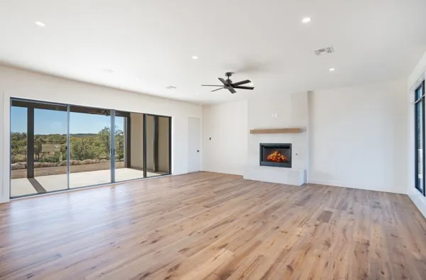 a view of an empty room with wooden floor and a fireplace