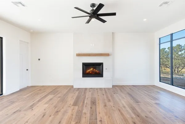 a view of an empty room with wooden floor and a fireplace