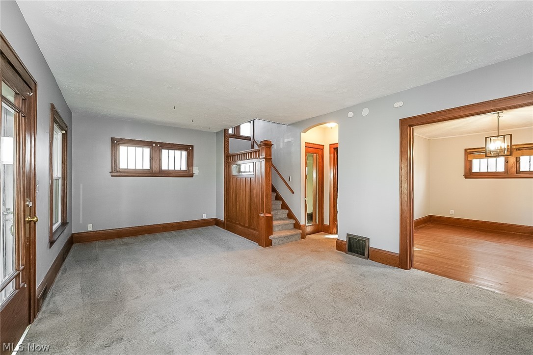 911 Dan Street Akron, OH 44310 - Photo 4 of 20 Empty room with light colored carpet and a notable chandelier