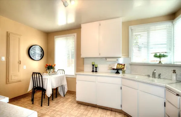 a kitchen with a sink cabinets a window and a clock