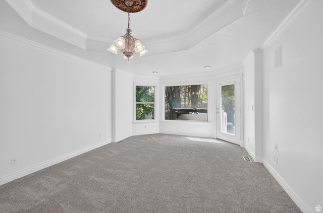 883 East 700 South Springville, UT 84663 - Photo 15 of 59 Spacious room featuring a tray ceiling with crown molding, a decorative chandelier with a ceiling medallion, bay windows, and a glass-paneled exterior door