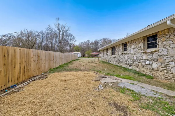 a backyard of a house with large trees and wooden fence